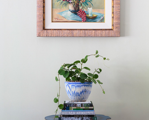 Touch Interiors rattan framed still life artwork with pot plant and blue side table