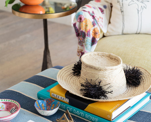 Touch Interiors straw hat, coffee table books and palm tree pillow