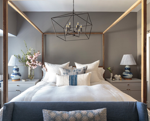 Dreamy bedroom with denim blue sofa at end of bed and large oversized black metal wire pendant light