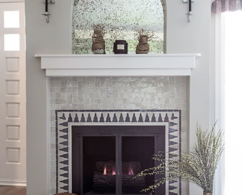 Fireplace with hand made Moroccan tile and antique shaped mirror and candle sconces in silver