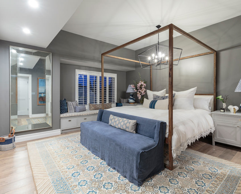 Stunning bedroom design with blue and gray rug, four poster bed made from reclaimed wood, oversized wire pendant light