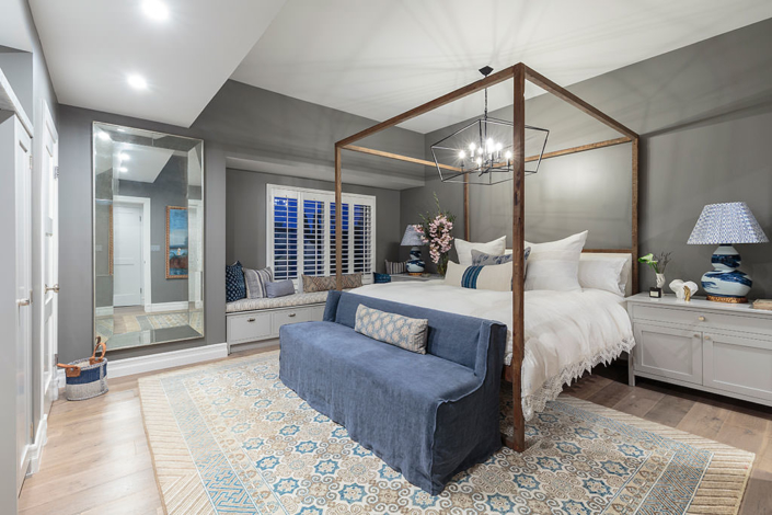 Stunning bedroom design with blue and gray rug, four poster bed made from reclaimed wood, oversized wire pendant light