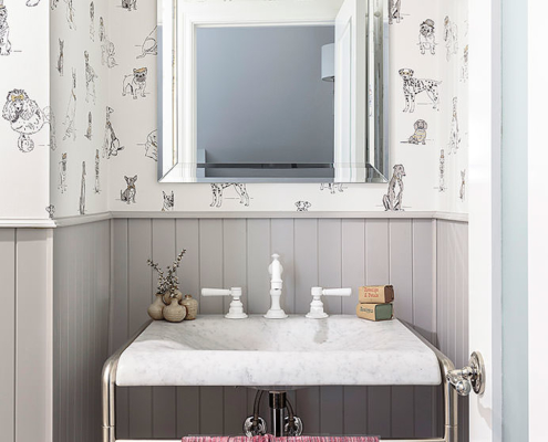 Carrara marble vanity with white faucet, light from Stahl and Band, dog wallpaper from Anthropologie, wainscot panelling