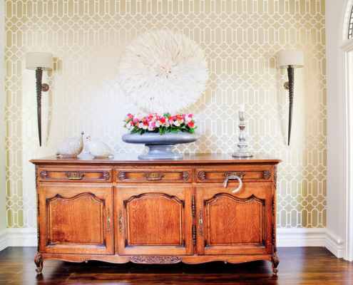 Designer Guild wallpaper with horn wall sconces and antique sideboard