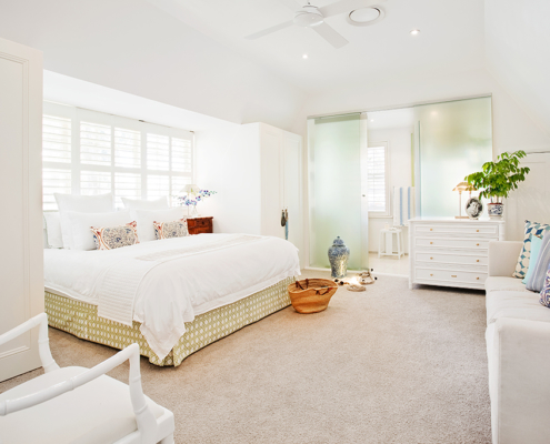White bedroom with king size bed and white bamboo Chippendale chair
