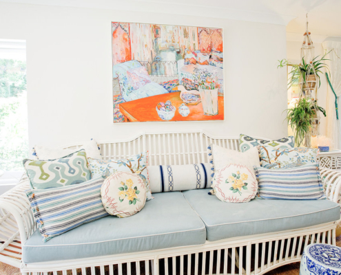 Cane sofa with colorful pillows and art by Eva Hannah
